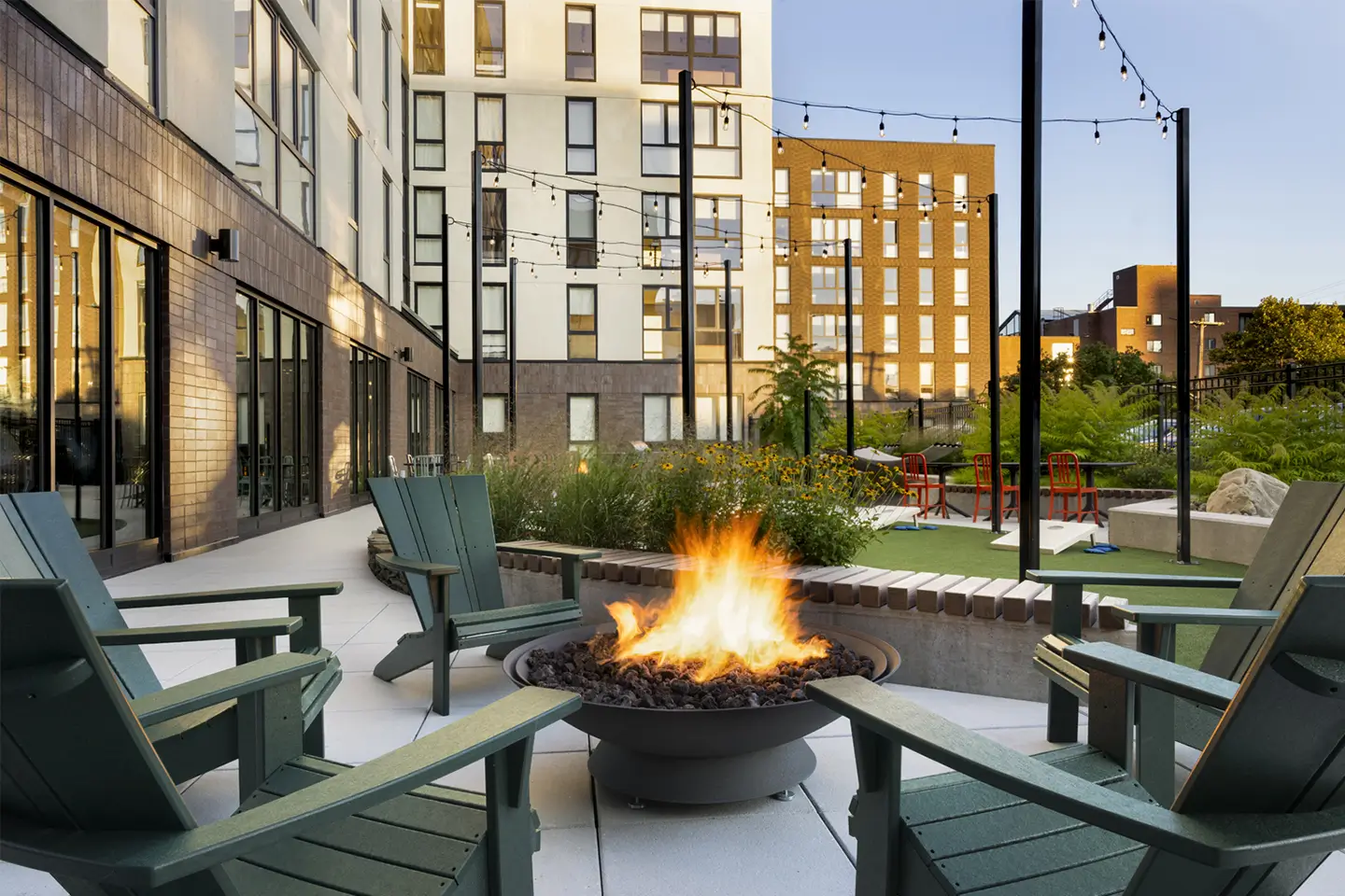 Outside area with string lights, fire pit, and comfortable seating.