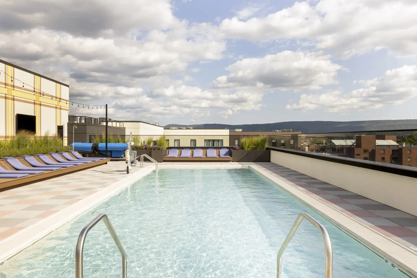 Rooftop pool with various loungers surrounding it.